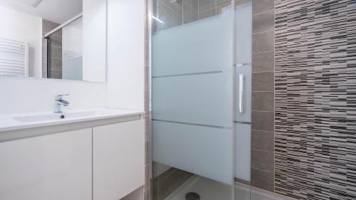 une salle de bain blanche avec un lavabo et une douche dans l'établissement La Dune N64 Villa 3P6, à Sérignan