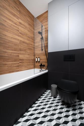a bathroom with a black toilet and a black and white floor at Apartamenty Rocha in Pabianice