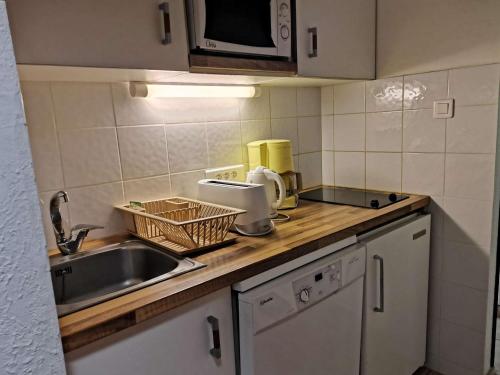 un comptoir de cuisine avec un évier et un micro-ondes dans l'établissement Studio 4 pers, pied des pistes, cuisine équipée, balcon sud - FR-1-404-92, à La Mongie