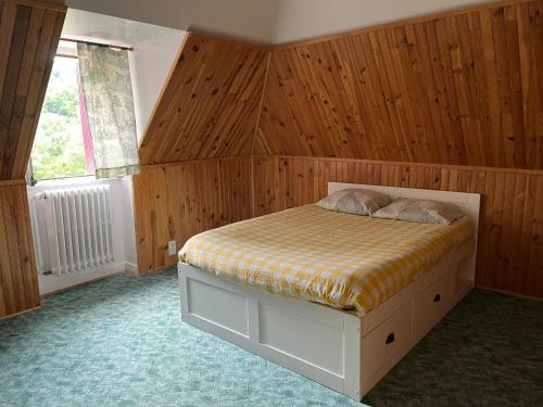 a bedroom with a bed with wooden walls and a window at Gîte-Auberge du Pont de Lanau in Neuvéglise