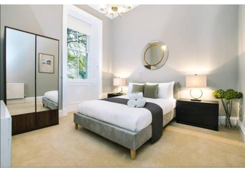 a bedroom with a large bed and a mirror at JOIVY Elegant New Town Flat near Princes Street in Edinburgh