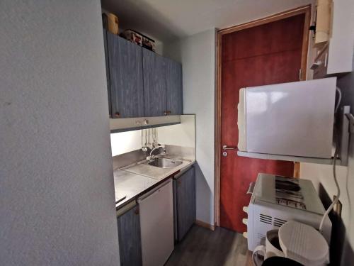 Il comprend une petite cuisine avec un évier et une porte rouge. dans l'établissement Studio 4 pers, pieds des pistes avec balcon et animaux admis - La Mongie - FR-1-404-5, à La Mongie