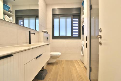 a bathroom with a toilet and a sink and a window at Alonim Privé in Gil‘am