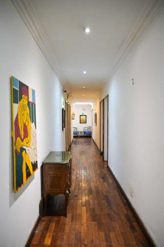 a hallway with white walls and wooden floors and paintings on the walls at Hotel Brajas in Antananarivo