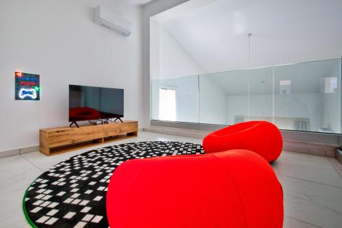 a living room with red chairs and a television at Aphrodite Gardens Modern Villas by VICHY Holidays in Paphos