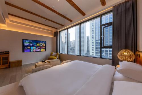 a bedroom with a large white bed and large windows at Shanheli Chaji Aesthetic Hotel Mixc Branch in Shantou
