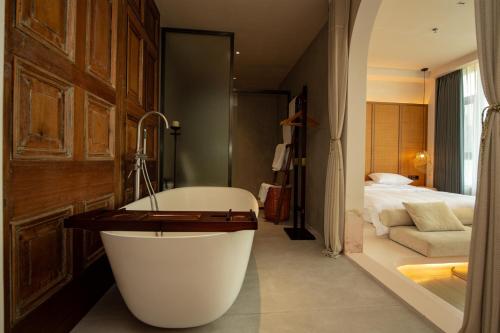 a bathroom with a bath tub and a bedroom at Shanheli Chaji Aesthetic Hotel Mixc Branch in Shantou