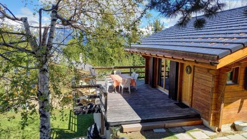 a cabin with a deck with a table and chairs at Chalet AS des Pics in Nendaz