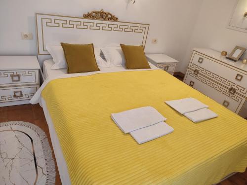 a bedroom with a large yellow bed with towels on it at Talia apartments & pool in Dobra Voda