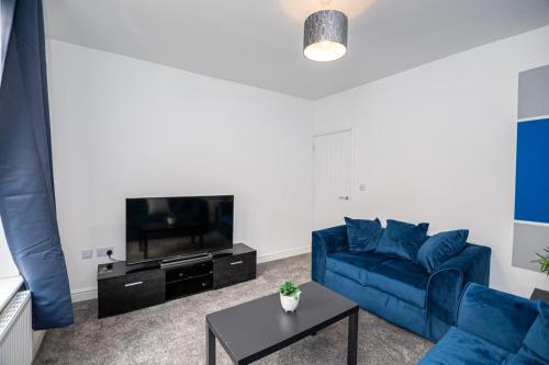 a living room with a blue couch and a tv at Bright Key Stays - The Lincoln Lodge at Spa Street in Lincoln