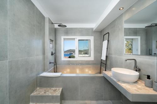 a bathroom with a tub and a sink and a bath tub at Elegant Coastal Retreat, Jacuzzi and Sea Views By KB Hospitality in Dhaskalión
