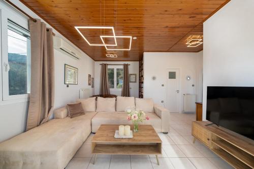 a living room with a couch and a tv at Elegant Coastal Retreat, Jacuzzi and Sea Views By KB Hospitality in Dhaskalión