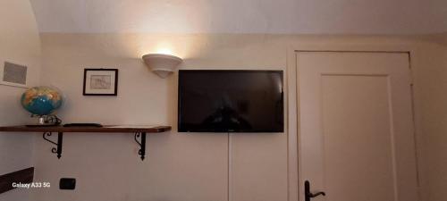a flat screen tv on a wall next to a door at Oryza Guest House in Desana
