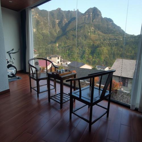 a room with a table and chairs and a mountain at Cloud House Of Leisurely in Zhangjiajie