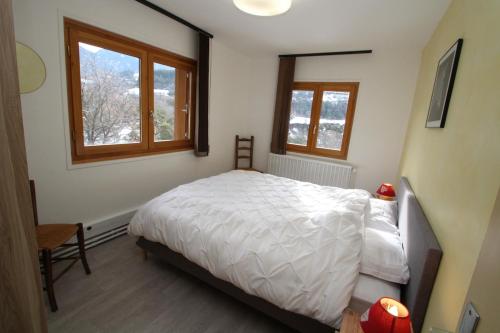 1 Schlafzimmer mit einem weißen Bett und 2 Fenstern in der Unterkunft Apartment LA ROCHETTE free parking on site in Guillestre