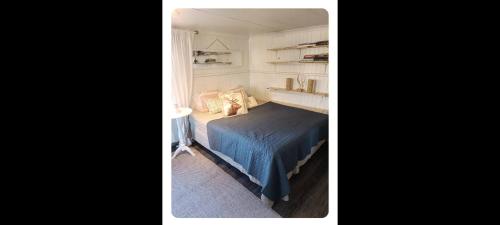 a bedroom with a blue bed and a window at Drängstugan in Kolbäck