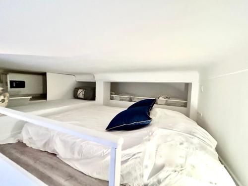 - un lit blanc avec un oreiller bleu dans la chambre dans l'établissement City Center Studio - 1 min Train Station & Main Street, à Nice