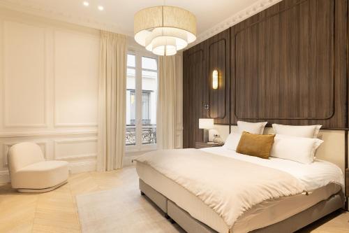 une chambre avec un grand lit et une chaise dans l'établissement Maison Galante - Serviced Apartments in Champs-Elysées, à Paris