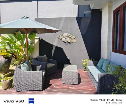a patio with two chairs and an umbrella at villa Nusantara ungasan in Uluwatu