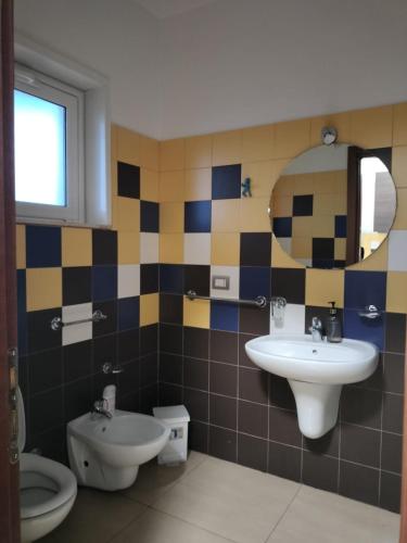 a bathroom with a sink and a toilet and a mirror at Corniola wellness & spa in Furnari