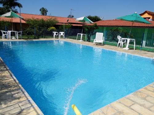 a large blue swimming pool with chairs and umbrellas at Pousada das Acerolas in Penedo