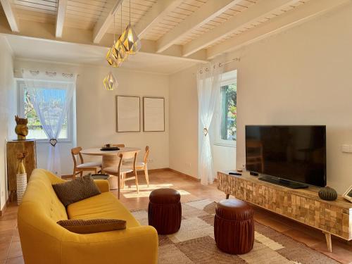 a living room with a yellow couch and a flat screen tv at Musa do Pico in Madalena
