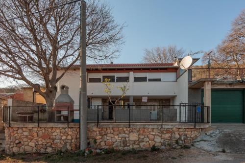 a house with a stone wall and a fence at Vulića dolac in Jasenice