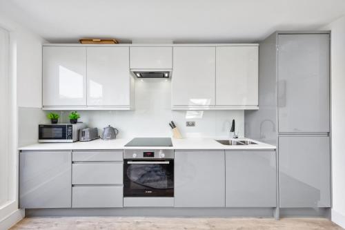 a white kitchen with white cabinets and a sink at Rockstar Greyz - Sleeps 7 - Central in The Hyde