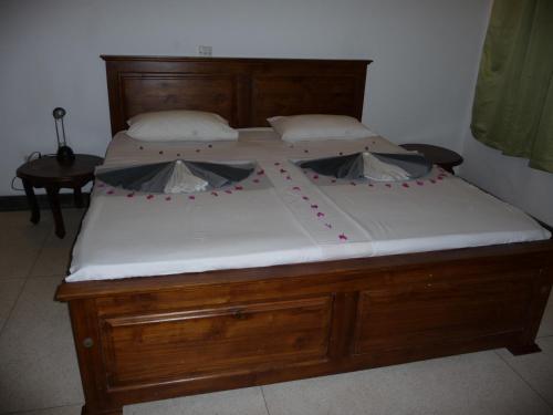 a large bed with a wooden frame and white sheets at Cinnamon Bungalow in Negombo