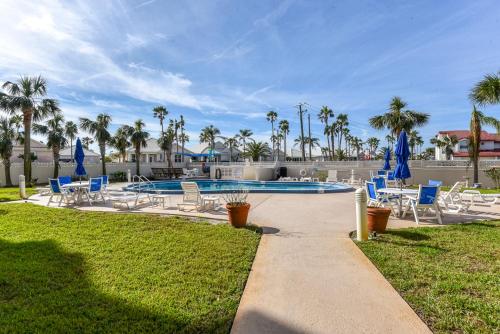 a swimming pool with blue chairs and a yard with palm trees at King's Hideaway in Daytona Beach Shores