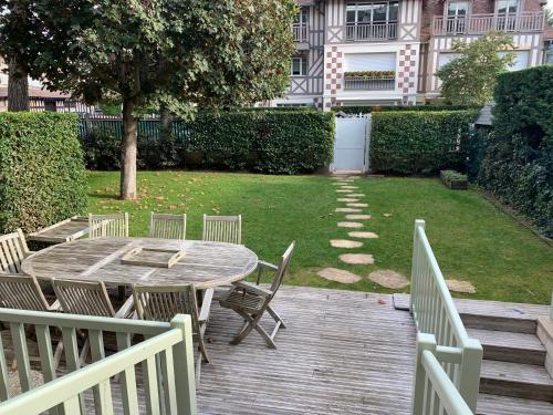 - une terrasse en bois avec une table et des chaises sur la cour dans l'établissement Appartement Deauville, à Deauville