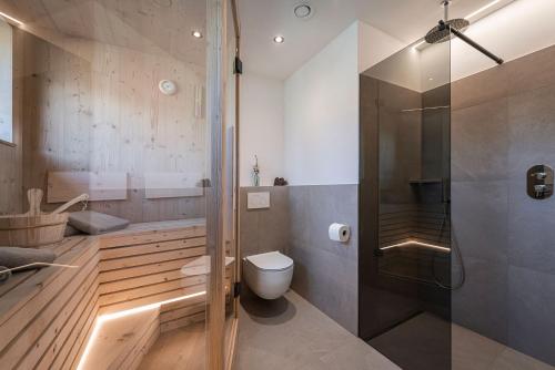 a bathroom with a toilet and a glass shower at Steindlgut - Weinberg Chalets in Brixen