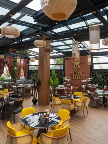 a restaurant with yellow chairs and tables and tables and chairs at DAMAC Maison Aykon City Dubai in Dubai