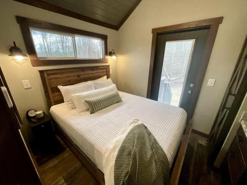 a bedroom with a bed with white sheets and a window at Breathtaking Tiny House Settled Between Trees in Tracy City, Tennessee in Tracy City