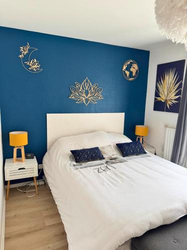 une chambre avec un grand lit avec un mur bleu dans l'établissement Lotus - Terrasse - Piscine - Parking, à Dax