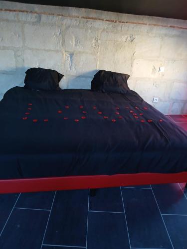 - un lit avec une couette noire et un cadre rouge dans l'établissement La chambre des plaisirs secrets, à Manduel