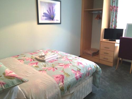 a bedroom with a bed with a floral bedspread and a desk at Luther King House in Manchester