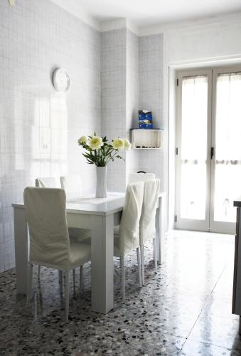 a white dining room table with white chairs and a vase of flowers at Calabrese Family in Pompei