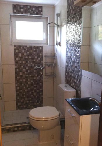 a bathroom with a toilet and a window and a sink at Agrelia House in Ouranoupoli