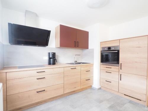 a kitchen with wooden cabinets and a tv on the wall at Ferienhaus im Weindorf -4 Erw 2 Ki- in Kappelrodeck
