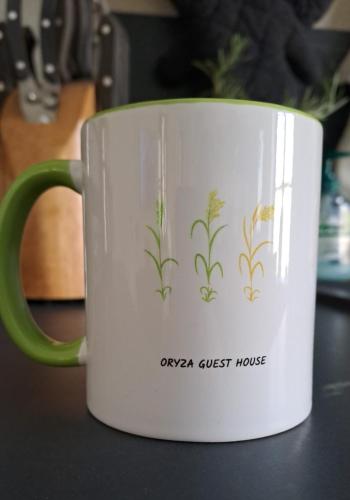 a coffee cup with plants on it on a table at Oryza Guest House in Desana