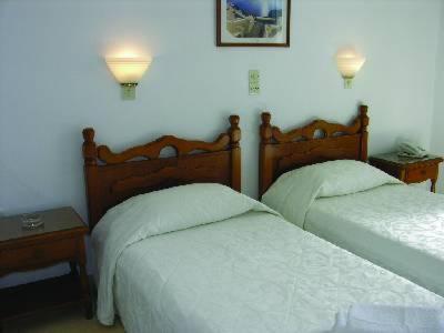 two beds in a bedroom with two lamps on the wall at Atlantis Hotel in Naousa