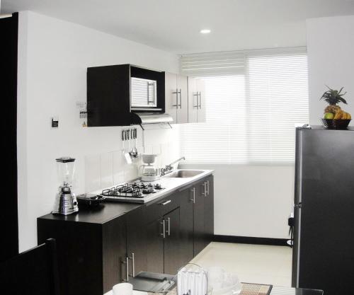a kitchen with black cabinets and a sink and a refrigerator at Aparthotel 2km Parque del Café BOOKUTRIP - 311-227-59-73 in Montenegro