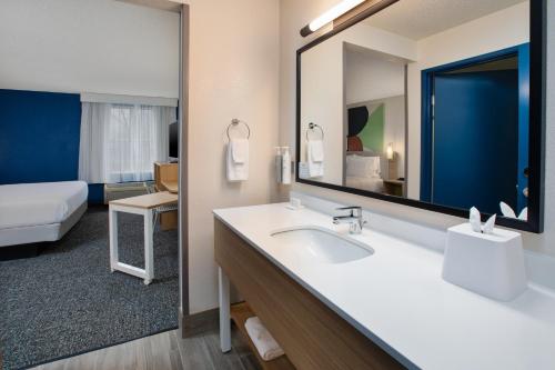a bathroom with a sink and a large mirror at Spark by Hilton Walker Grand Rapids North in Grand Rapids