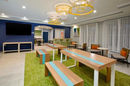 a waiting room with tables and chairs and a flat screen tv at Spark by Hilton Walker Grand Rapids North in Grand Rapids