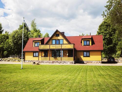 a large yellow house with a red roof at Pusi Holiday House in Pusi