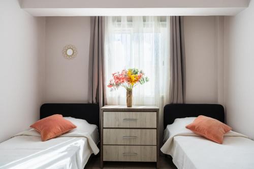 two beds in a room with a vase of flowers at Carisa flat, 2 bedrooms in Larnaca