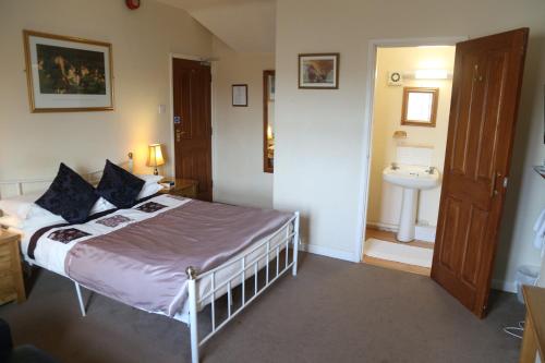 a bedroom with a bed and a bathroom with a sink at All Seasons Guest House in Oxford