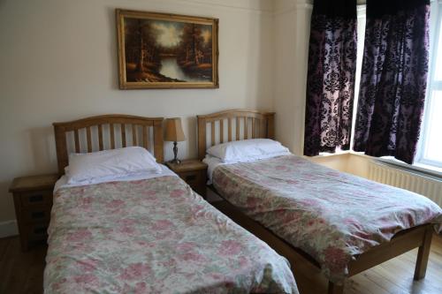 a bedroom with two beds and a picture on the wall at All Seasons Guest House in Oxford