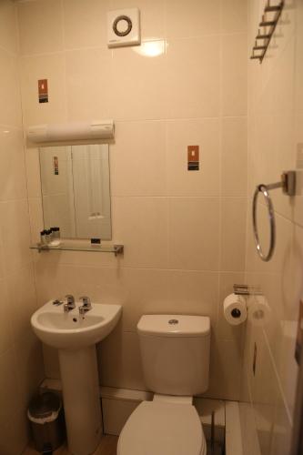 a bathroom with a toilet and a sink and a mirror at All Seasons Guest House in Oxford